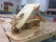 a house made out of wood sitting on top of a workbench in a shop