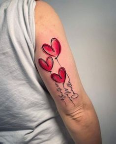 a woman's arm with three red hearts and the words love is in the air