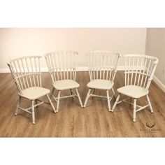 four white chairs sitting on top of a hard wood floor