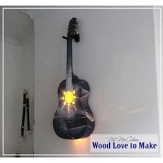 a guitar shaped light hanging from the side of a white wall with words wood love to make on it