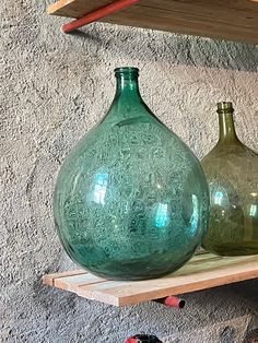 two green vases sitting on top of a wooden shelf