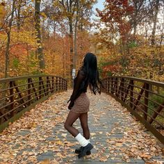 a woman is standing on a bridge in the fall with leaves all over her feet