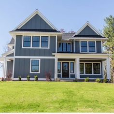 a large gray house sitting on top of a lush green field