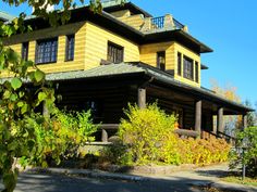 a large yellow house sitting on the side of a road in front of some trees