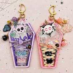 two key chains with charms attached to them on a pink surface and stars in the background