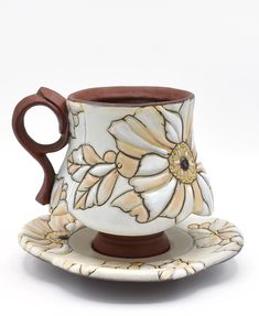 a coffee cup and saucer with flowers painted on the outside, sitting on a saucer