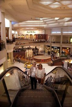 two women walking down an escalator in a mall