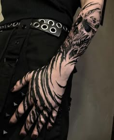 a person with black and white tattoos on their arm, holding onto a metal ring