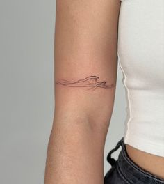 a woman's arm with a wave tattoo on the left side of her arm