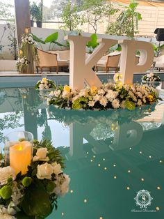 a table with flowers and candles on it next to a large letter that says klp