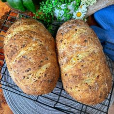 two loaves of bread sitting on top of a cooling rack next to some flowers