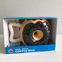 there is a coffee mug with a doughnut in the box next to it,