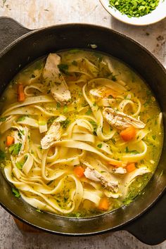 chicken noodle soup with carrots and parsley in a skillet