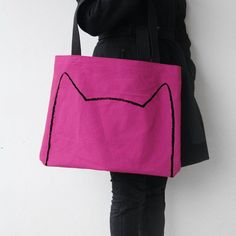 a woman is holding a pink bag with a cat drawn on it