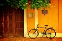 a bicycle is parked in front of an orange building with two doors and a tree