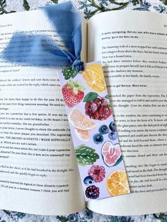 an open book with fruit stickers on it and a blue ribbon tied to the cover