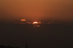 the sun is setting behind some clouds in the sky