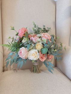 a bouquet of flowers sitting on top of a beige chair next to a white wall