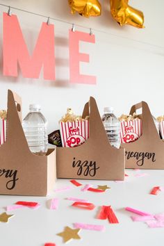 three bags with popcorn are sitting on a table near confetti and streamers