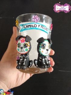 a hand holding a glass with two dogs on it and the words camilo y pass