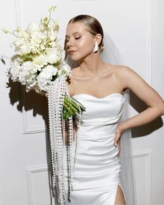 a woman in a white dress holding a bouquet of flowers and pearls on her wedding day