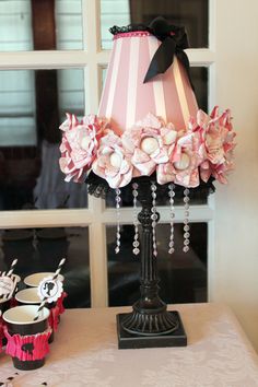 a lamp that is on top of a table next to cupcakes and other items