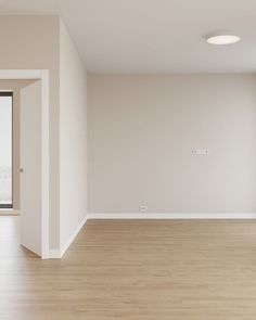 an empty room with white walls and wood flooring is seen from the doorway to the outside