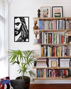 a bookshelf filled with lots of books in a living room next to a window