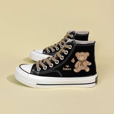 High-top black canvas sneakers with an adorable bear graphic and brown laces. Durable white rubber sole with black stripes, offering a playful yet stylish look for everyday wear. Bear print detail at side Lace up at top Canvas fabric Cotton lining Bear Black And White, Anting Manik, Black Casual Shoes, Mode Shoes, Kawaii Shoes, White High Tops, Black Shoe, Cute Sneakers, Aesthetic Shoes