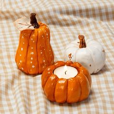 three small pumpkins sitting on top of a checkered tablecloth covered table cloth