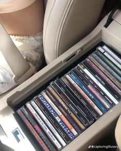 a bunch of cds are sitting in the back seat of a car and it's tray is filled with them