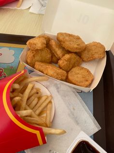 chicken nuggets and french fries on a tray with ketchup in a container