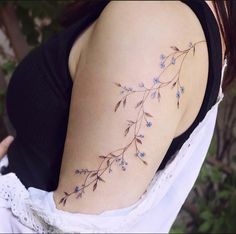 a woman with a tattoo on her shoulder has blue flowers growing out of the side