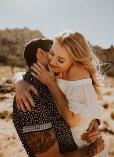 a man and woman embracing each other in the desert