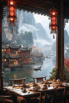 an outdoor restaurant overlooking the water with lanterns hanging from it's ceiling and tables set for two