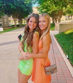 two young women hugging each other on the sidewalk