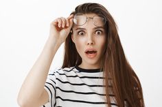 a woman with glasses making a surprised face while holding her hair in front of her head