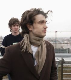 two young men standing next to each other in front of a cityscape,