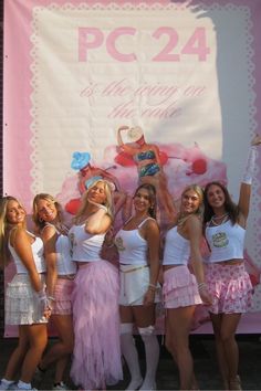 a group of women standing next to each other in front of a large sign that says pc 24