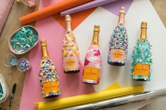 there are four bottles that have been decorated with beads and confetti on them