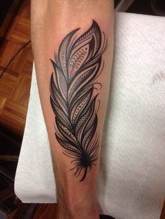 a black and white feather tattoo on the leg