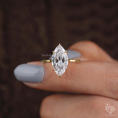 a woman's hand holding a ring with a pear shaped diamond on it,