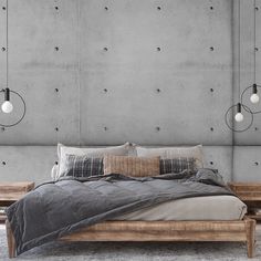 a bedroom with concrete walls and flooring is pictured in this image, there are three lamps hanging above the bed