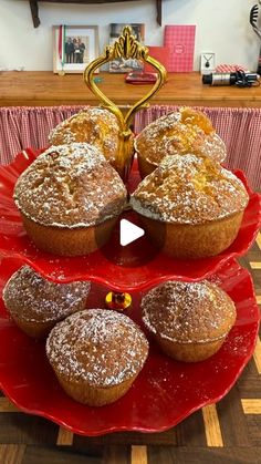 a red plate topped with muffins covered in powdered sugar