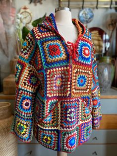 a colorful crocheted jacket is on a mannequin's head stand