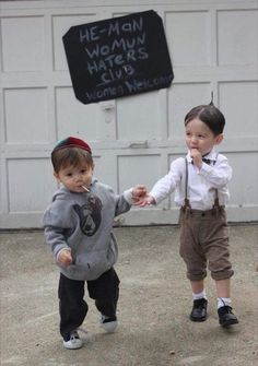 two small children holding hands in front of a sign that says he man woman haters