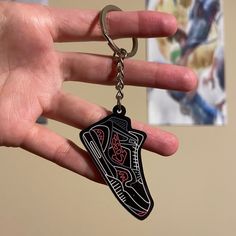 a hand holding a key chain with a shoe design on it