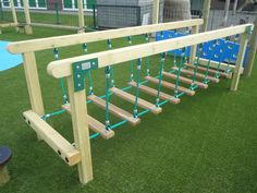 a wooden bench sitting on top of a lush green field next to a blue trampoline