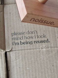 a piece of wood sitting on top of a cardboard box that says, please don't mind how i look i'm being reused