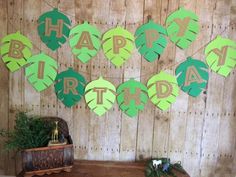 a wooden table topped with lots of green paper cut outs and happy birthday letters on it